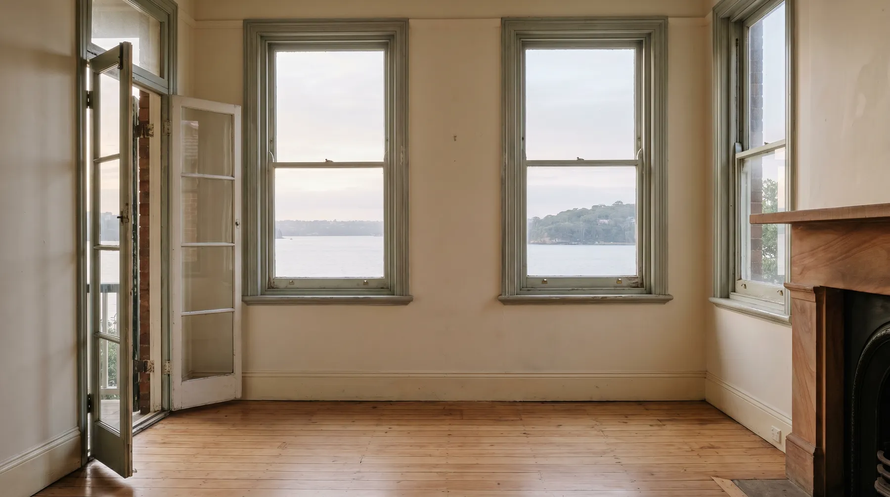 An emptied, freshly swept living room in an older Mosman house, morning light and harbour water through the sash windows